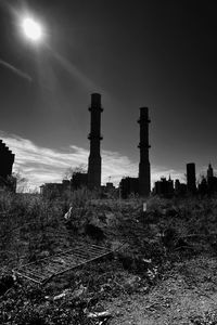 Abandoned factory by field against sky