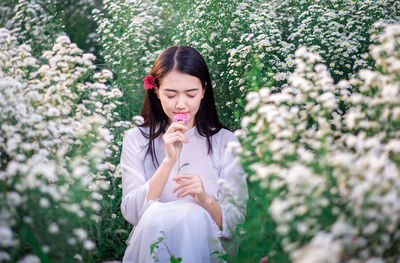 Full length of woman standing by white flowering plants