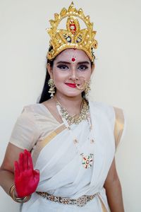 Portrait of smiling young woman wearing sari and jewelries standing against white background