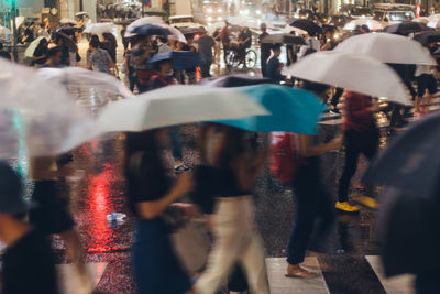 People walking with umbrella on street at night