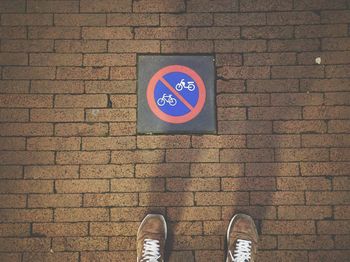 Low section of man standing by warning sign on footpath