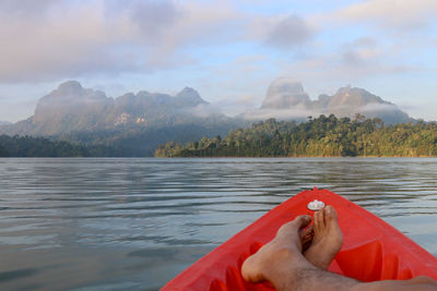 Low section of man by lake against mountain range