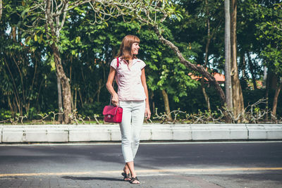 Full length of woman on road against trees in city