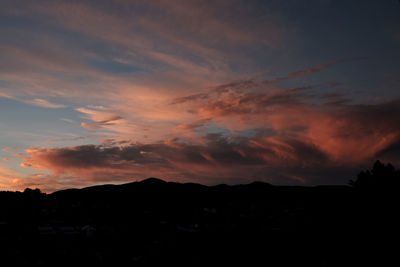 Silhouette trees against dramatic sky during sunset