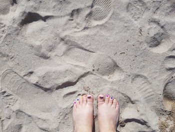 Low section of woman standing on sand