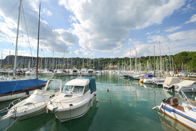 Boats moored at harbor against sky