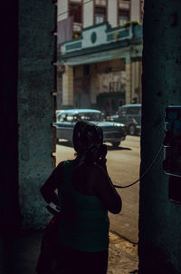 Woman talking on payphone in city