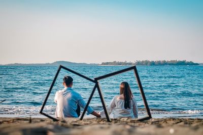 Rear view of couple sitting on beach