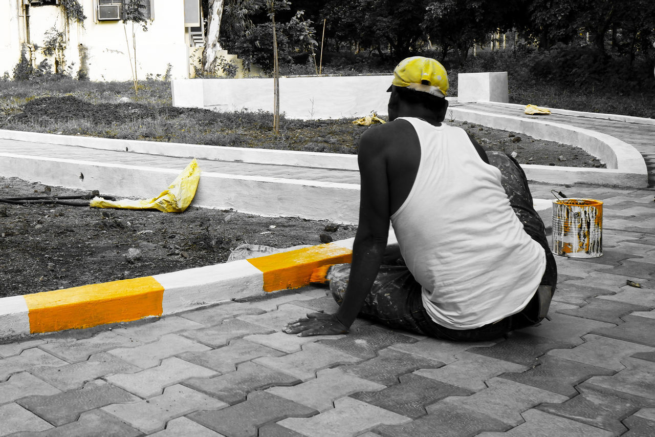 REAR VIEW OF MAN WORKING ON STREET AT CITY