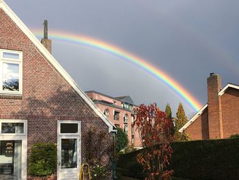 Low angle view of rainbow over buildings against sky