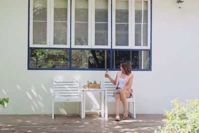 Young woman sitting on chair by window