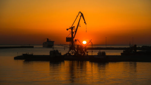 Backlit cranes and ship in the port at sunrise with fire sky