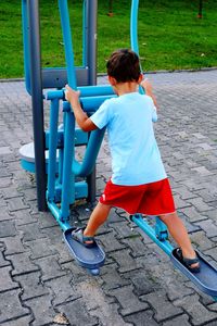 Rear view of boy playing on outdoor play equipment at playground