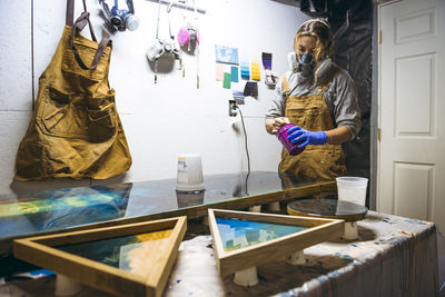 Female resin artist mixing with respirator mask