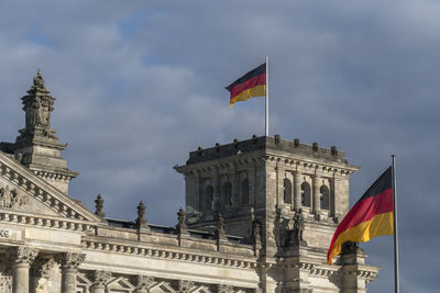 Low angle view of flags against cloudy sky