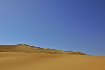 Scenic view of desert against clear blue sky