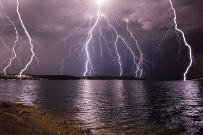 Lightning in cloudy sky over sea at night