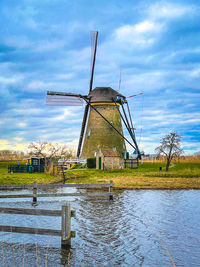 Traditional windmill on landscape against sky