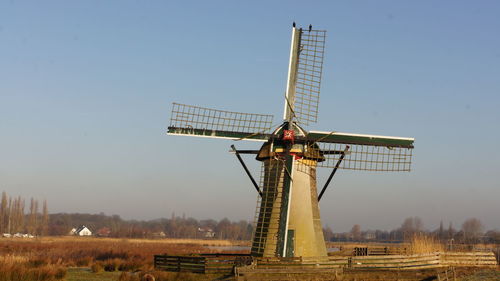 Traditional windmill on field against clear sky