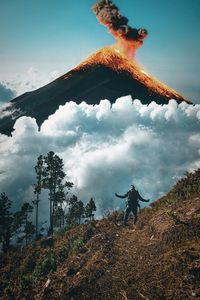Low angle view of man standing on land against an active volcano in guatemala