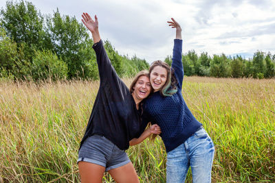 Group of two girl friends sisters dancing hugging and having fun together in nature outdoors