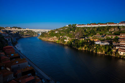 High angle view of townscape by sea against clear blue sky