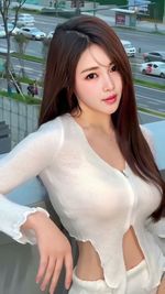 Portrait of young woman standing against wall