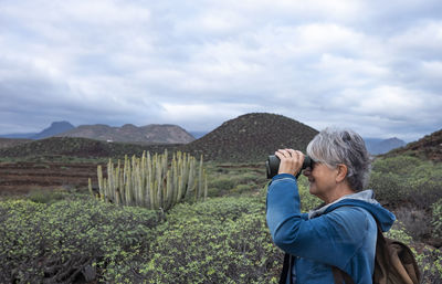 Rear view of woman standing on mountain against sky