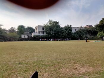 Group of people on field against built structure