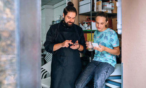 Cook and waitress looking mobile during pause