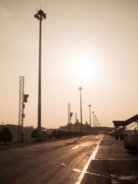 Street lights on airport road against sky during sunrise