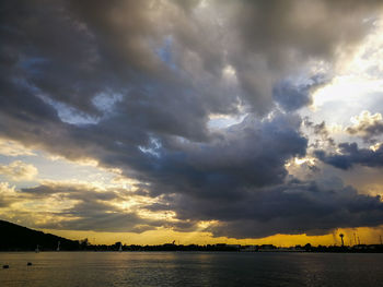 Scenic view of lake against dramatic sky during sunset