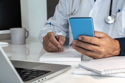 Midsection of doctor working on table