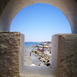 People on beach against clear blue sky