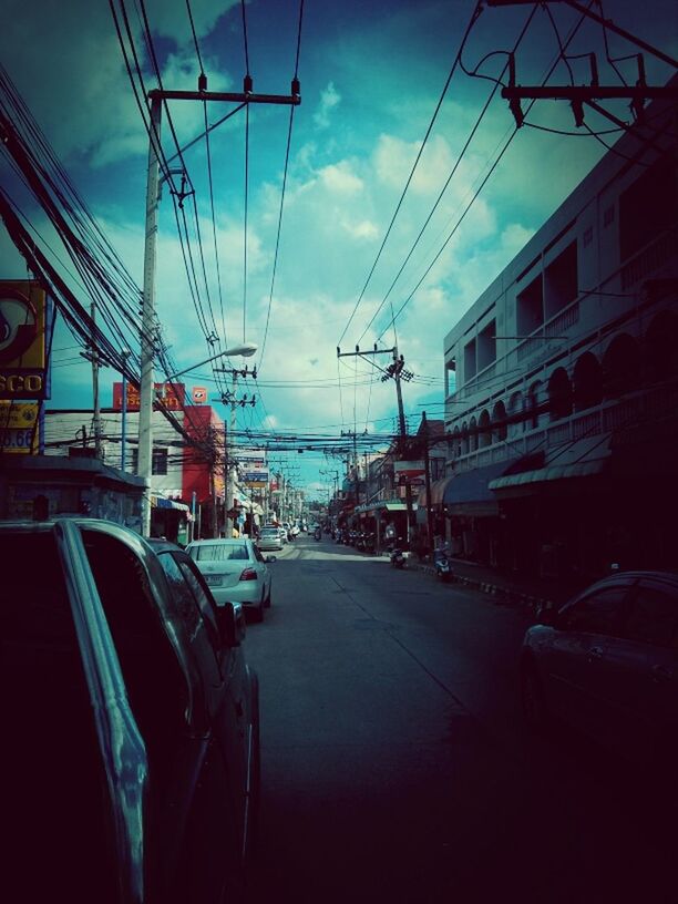 transportation, sky, power line, electricity pylon, mode of transport, building exterior, built structure, architecture, cable, car, land vehicle, the way forward, diminishing perspective, cloud - sky, power supply, electricity, cloud, railroad track, street, road