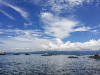 Sailboats moored in sea against sky