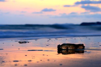 Surface level of beach against sky during sunset