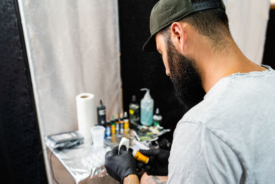 Side view of tattoo artist holding bottle in workshop