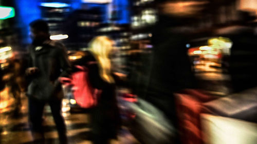 Blurred motion of people in illuminated city at night