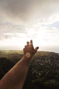 Close-up of hand against sky during sunset