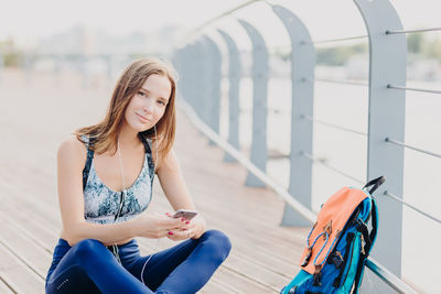 Young woman smiling while sitting on railing