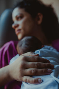 Close-up of woman sitting with newborn son in hospital