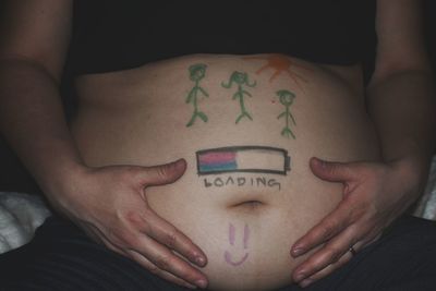 Midsection of pregnant woman drawing on stomach