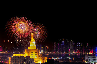 Firework display over illuminated buildings in city at night