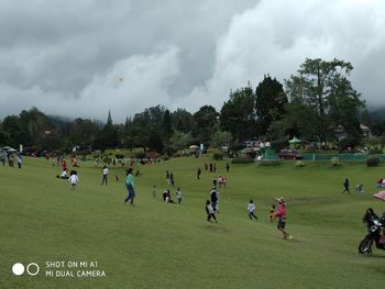 People playing on field against sky