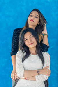 Portrait of beautiful woman standing against blue wall