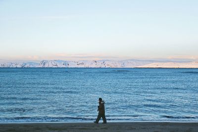 Rear view of man standing on beach against sky