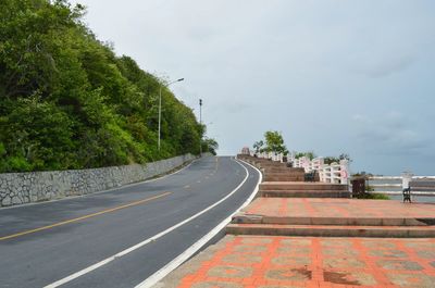 Road leading towards city against sky