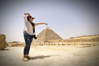 Optical illusion of woman holding pyramid against clear sky