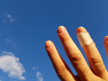 Close-up of hand against blue sky